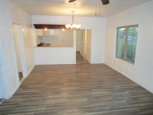 interior space with dark wood-type flooring, ornamental molding, and ceiling fan with notable chandelier