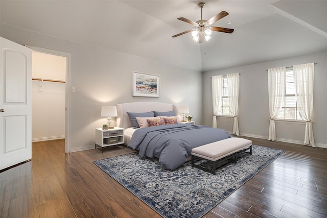 bedroom featuring dark wood-type flooring, ceiling fan, vaulted ceiling, a walk in closet, and a closet