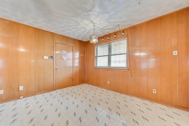 empty room featuring a chandelier and wood walls