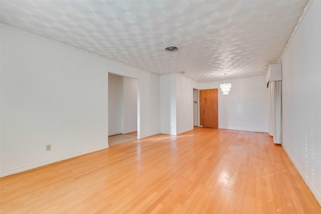 spare room with wood-type flooring, a notable chandelier, and a textured ceiling