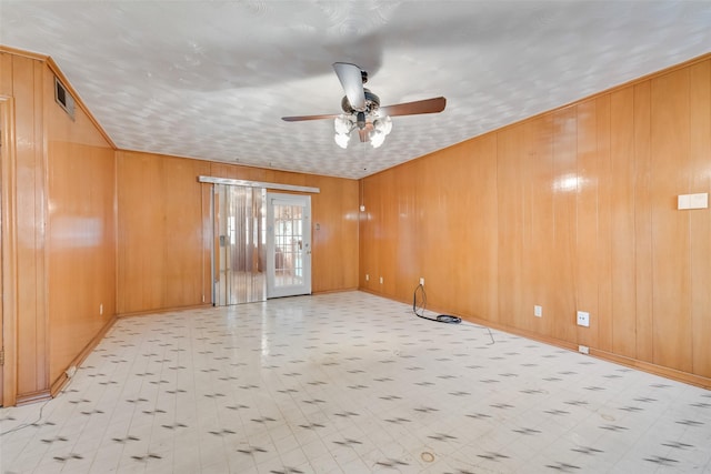 spare room featuring ceiling fan and wood walls