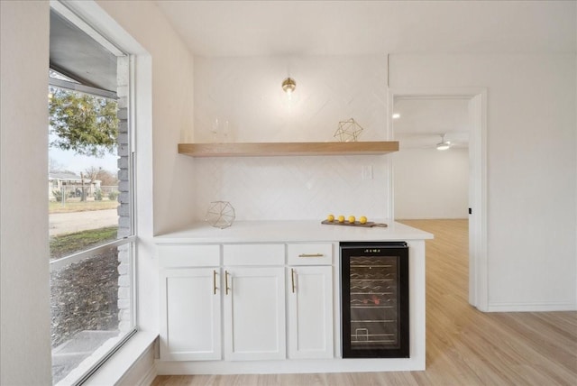 bar featuring white cabinets, tasteful backsplash, beverage cooler, and light hardwood / wood-style flooring