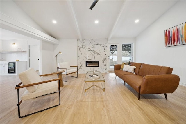 living room featuring lofted ceiling with beams, light wood-type flooring, wine cooler, and a fireplace