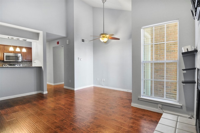 unfurnished living room with dark hardwood / wood-style flooring, high vaulted ceiling, and ceiling fan