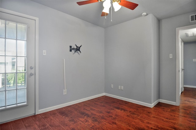 empty room with dark hardwood / wood-style flooring, plenty of natural light, and ceiling fan