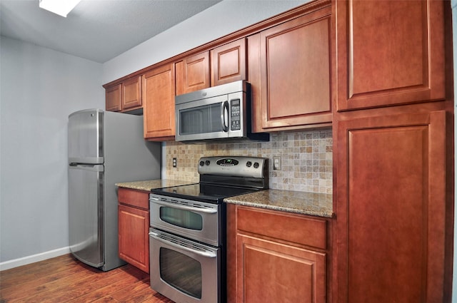 kitchen with dark wood-type flooring, stainless steel appliances, decorative backsplash, and stone counters