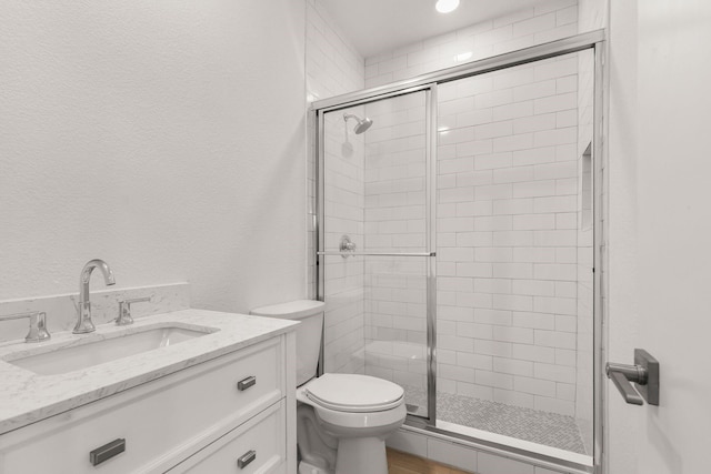 bathroom with vanity, toilet, and a shower with door