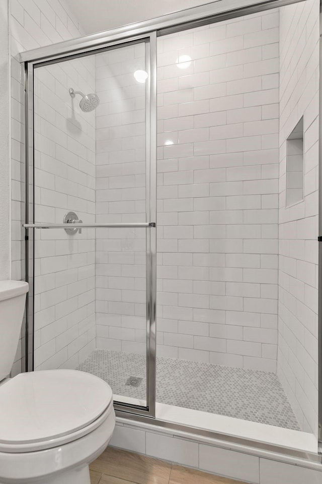 bathroom with toilet and a shower with shower door