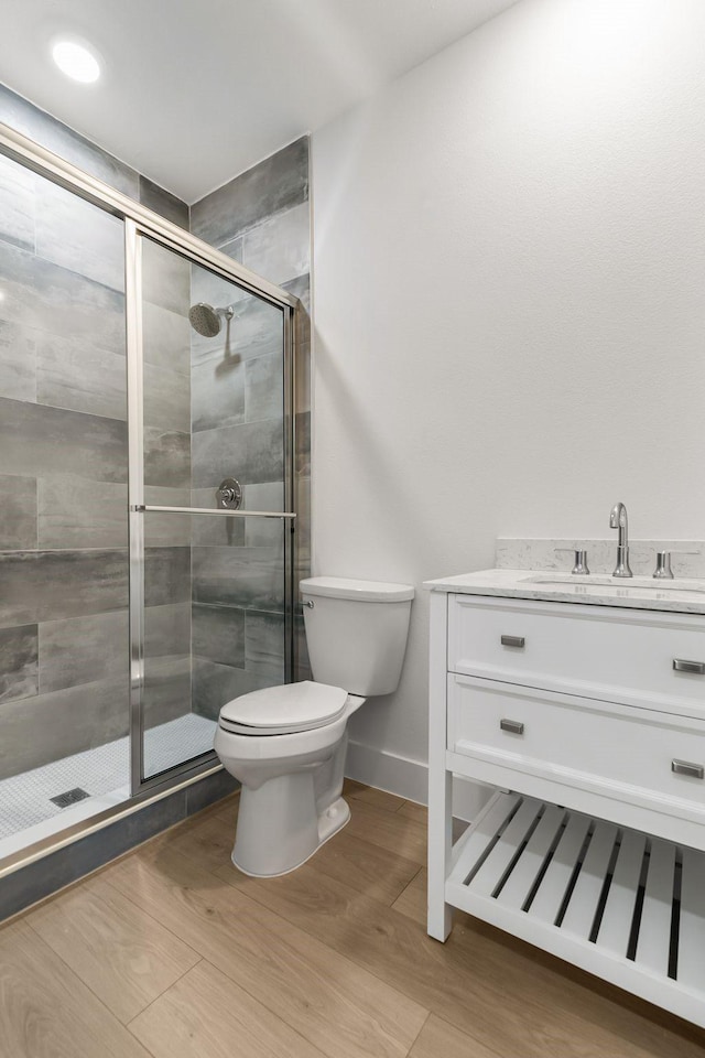 bathroom with hardwood / wood-style flooring, vanity, toilet, and a shower with shower door