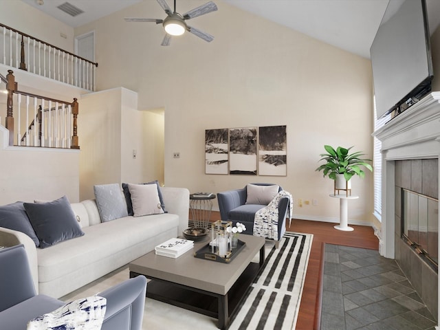 living room with a tiled fireplace, hardwood / wood-style floors, and high vaulted ceiling