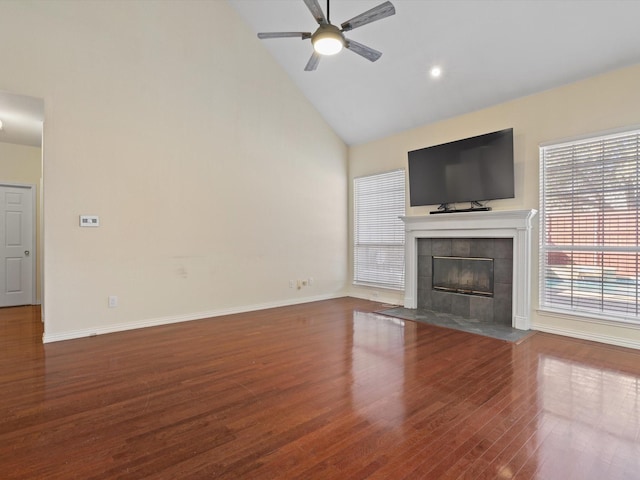 unfurnished living room with hardwood / wood-style floors, high vaulted ceiling, a tile fireplace, and ceiling fan