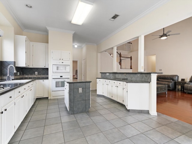 kitchen featuring white cabinetry, a kitchen island, sink, and oven