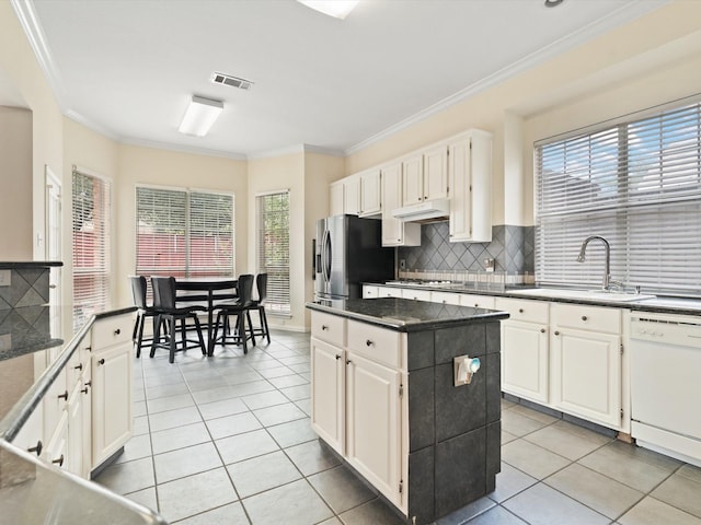 kitchen featuring light tile patterned flooring, sink, a center island, ornamental molding, and appliances with stainless steel finishes