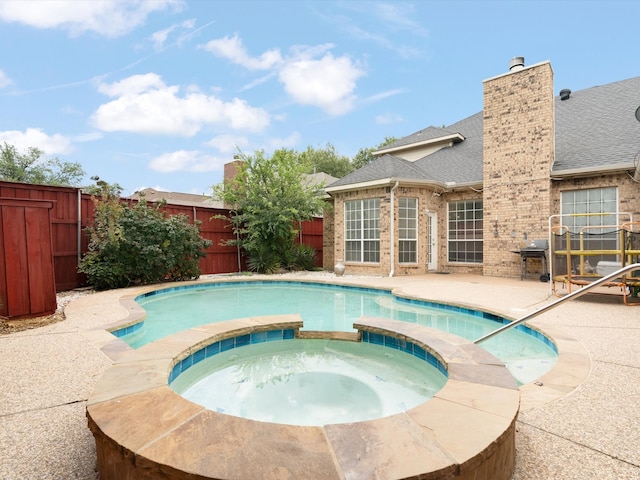 view of swimming pool with an in ground hot tub, a grill, and a patio