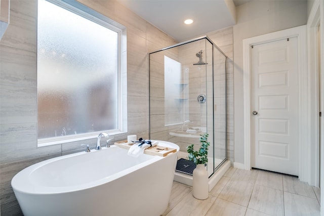 bathroom featuring shower with separate bathtub and tile walls