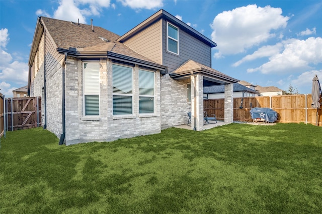 rear view of property with a yard and a patio area