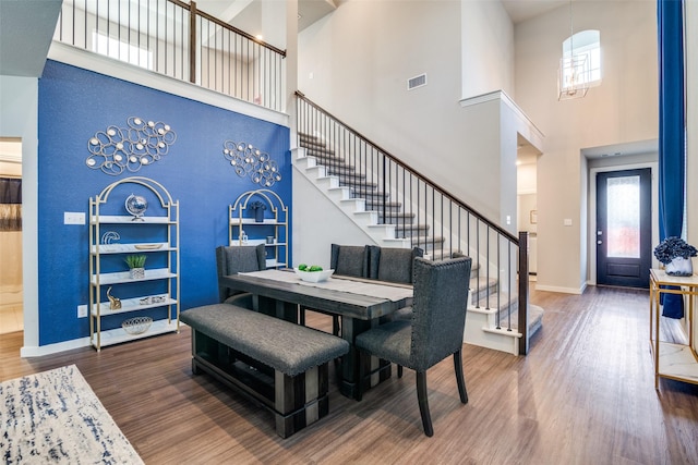 dining room with hardwood / wood-style flooring and a towering ceiling