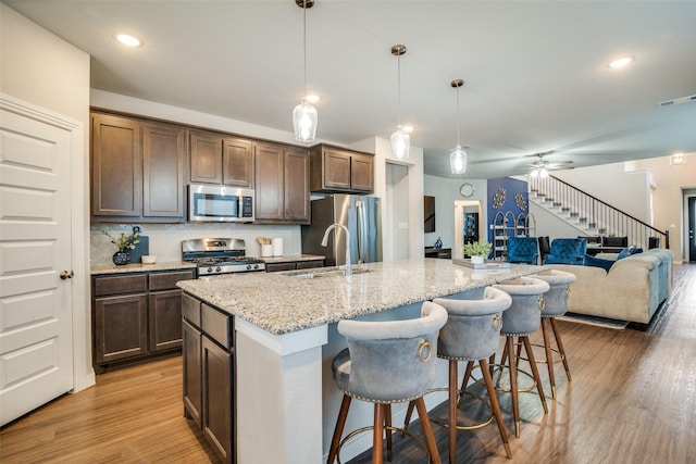 kitchen featuring pendant lighting, a breakfast bar area, stainless steel appliances, and an island with sink