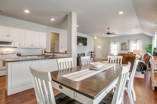 dining area featuring vaulted ceiling, sink, dark wood-type flooring, and ceiling fan