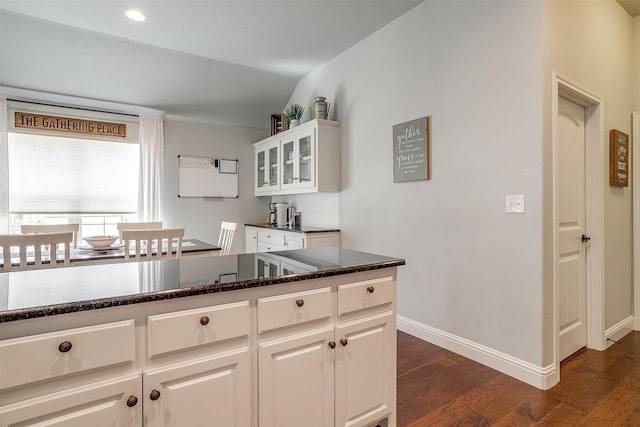 kitchen with white cabinetry, dark stone counters, and dark hardwood / wood-style floors