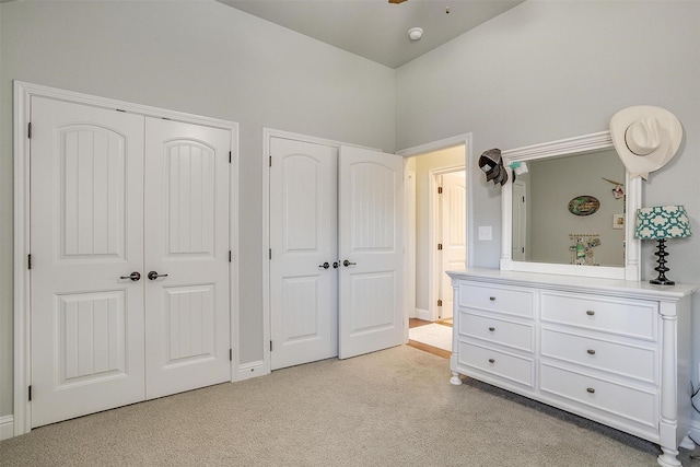 unfurnished bedroom with two closets and light colored carpet