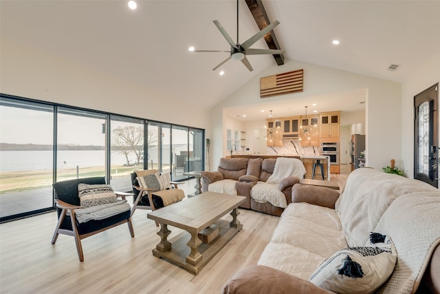 living room featuring a water view, light hardwood / wood-style flooring, ceiling fan, high vaulted ceiling, and beamed ceiling