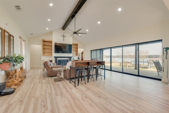 living room featuring ceiling fan, beamed ceiling, light wood-type flooring, and high vaulted ceiling