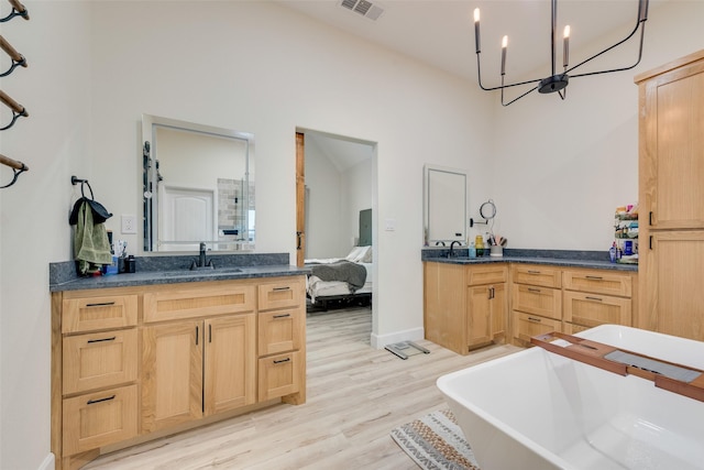 bathroom featuring a chandelier, wood-type flooring, a bathtub, and vanity