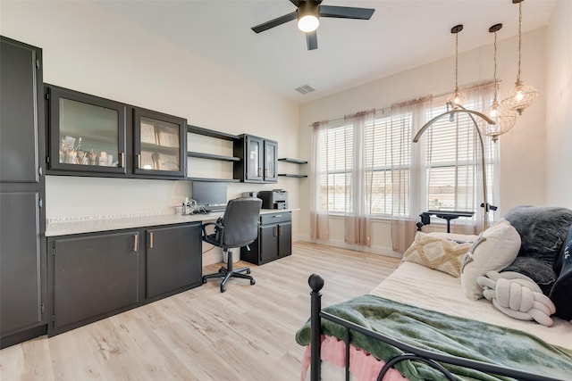 office area featuring vaulted ceiling, built in desk, and light hardwood / wood-style floors