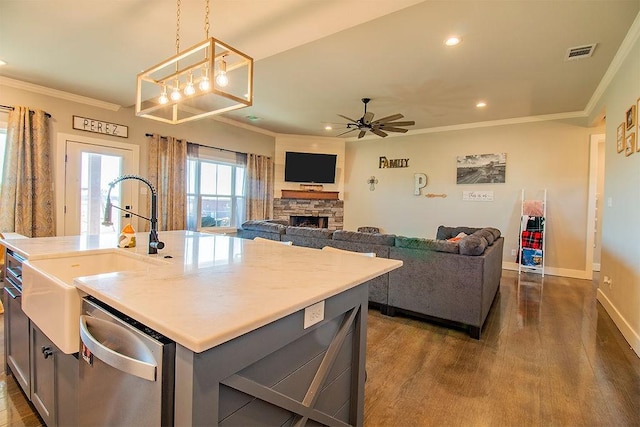 kitchen featuring sink, crown molding, decorative light fixtures, dishwasher, and an island with sink