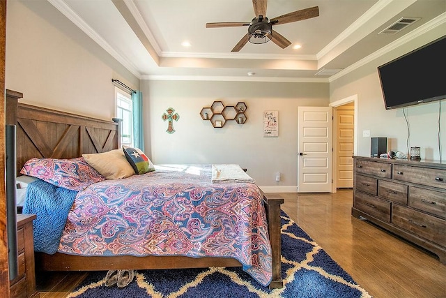 bedroom featuring light hardwood / wood-style flooring, ornamental molding, and a raised ceiling