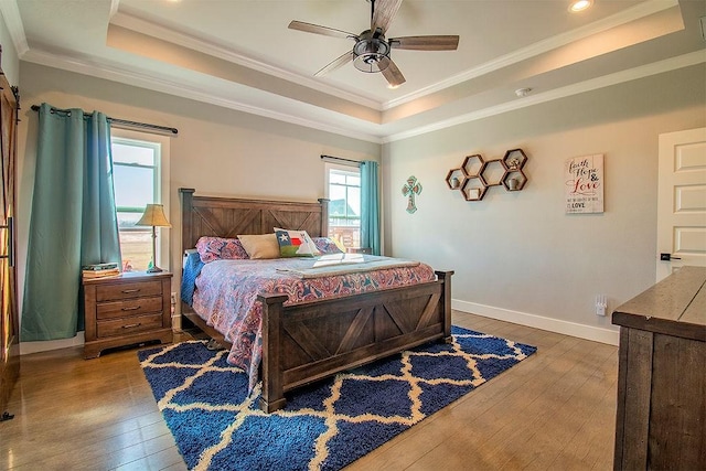 bedroom featuring crown molding, hardwood / wood-style floors, a tray ceiling, and ceiling fan