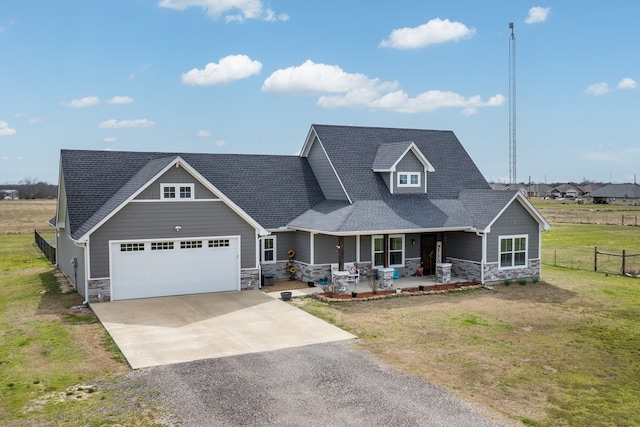 craftsman house with aphalt driveway, covered porch, a front yard, stone siding, and an attached garage