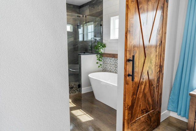 full bathroom with a shower stall, a soaking tub, and wood finished floors