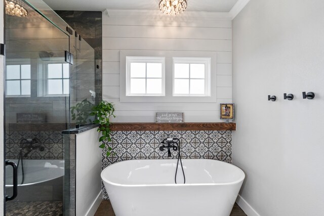 bathroom featuring a stall shower, crown molding, baseboards, and a freestanding bath