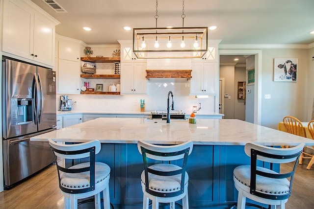 kitchen featuring a breakfast bar, pendant lighting, white cabinetry, stainless steel fridge with ice dispenser, and light stone countertops