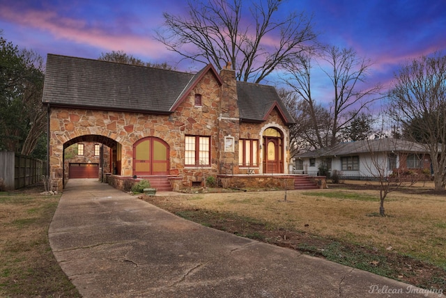 english style home with a garage and a yard