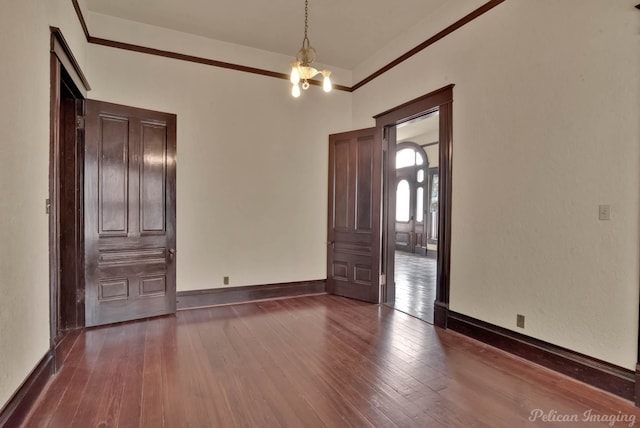 unfurnished room featuring a notable chandelier, crown molding, and dark hardwood / wood-style floors