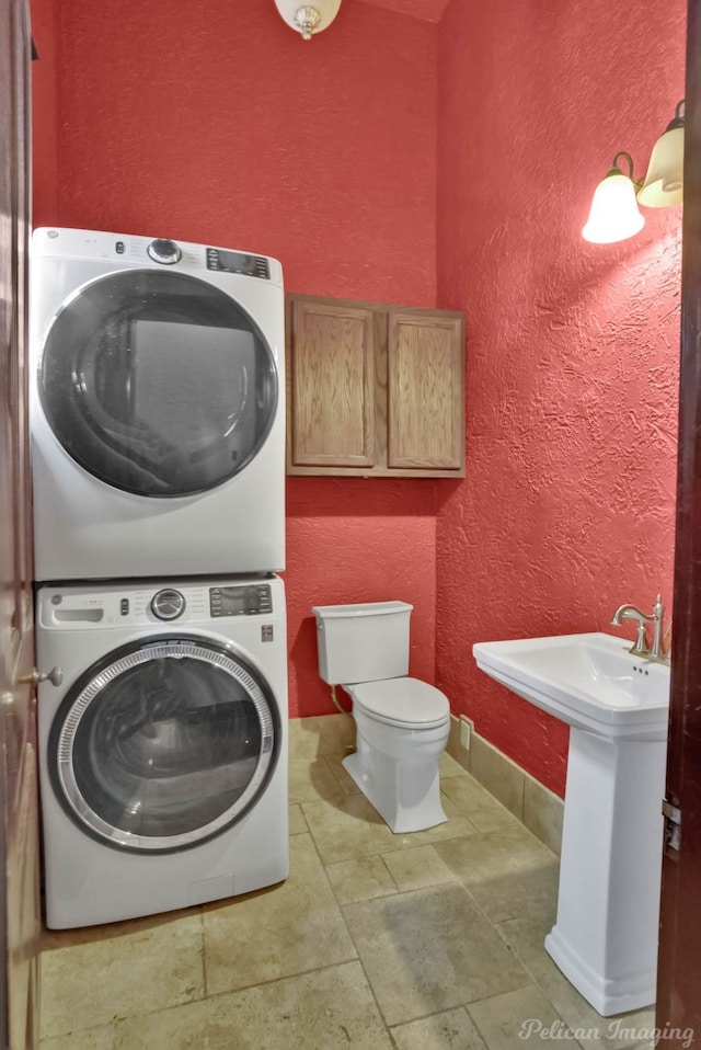 washroom with stacked washer and dryer and sink