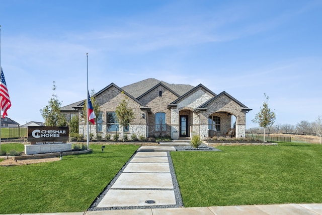 french country inspired facade with brick siding and a front yard