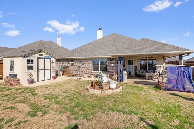 rear view of property featuring a storage unit, a yard, and a patio area