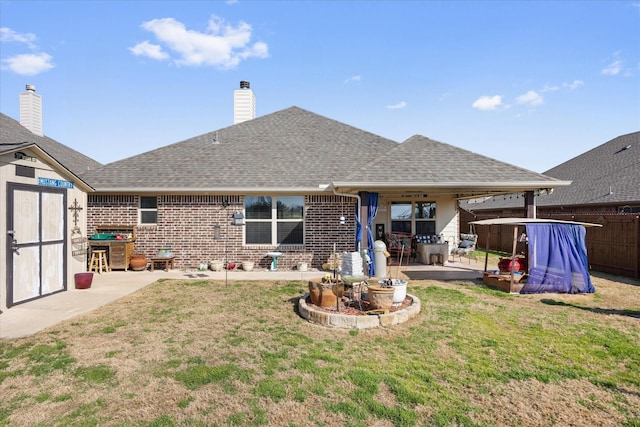 back of property featuring a patio, a yard, and a storage unit