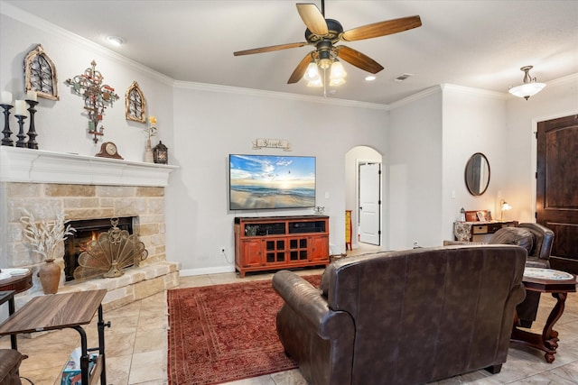 living room featuring light tile patterned floors, a fireplace, ornamental molding, and ceiling fan