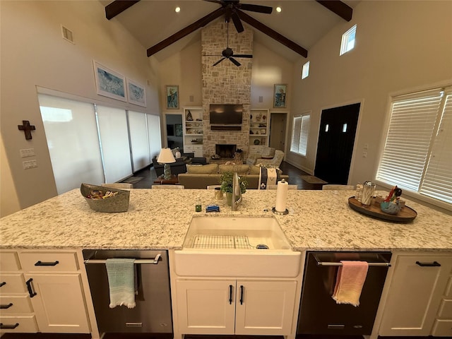 kitchen featuring white cabinetry, a fireplace, light stone countertops, and beam ceiling