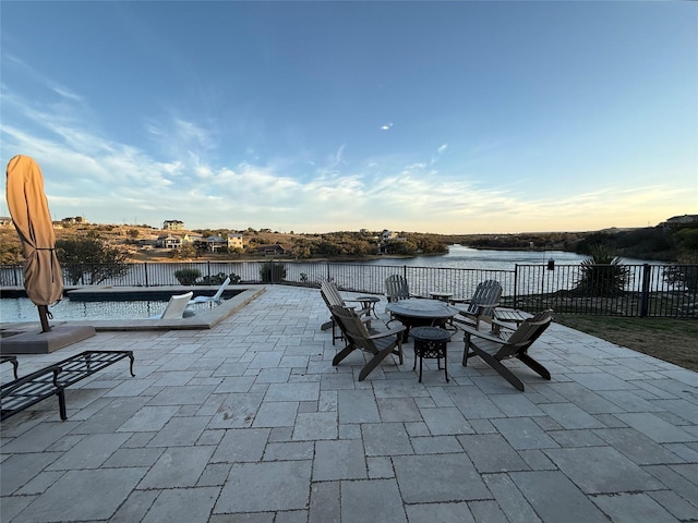 view of patio / terrace featuring a fenced in pool, a fire pit, and a water view