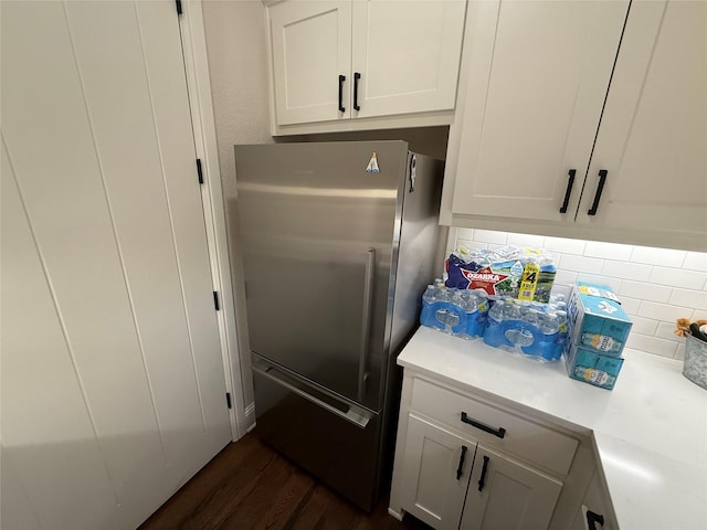 kitchen featuring white cabinets, tasteful backsplash, dark wood-type flooring, and stainless steel fridge