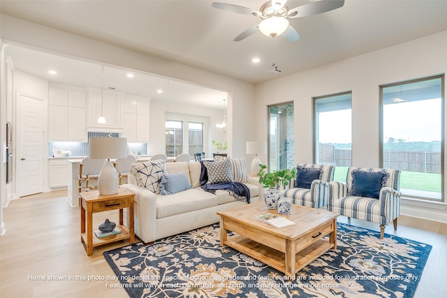 living room with ceiling fan, a healthy amount of sunlight, and light wood-type flooring