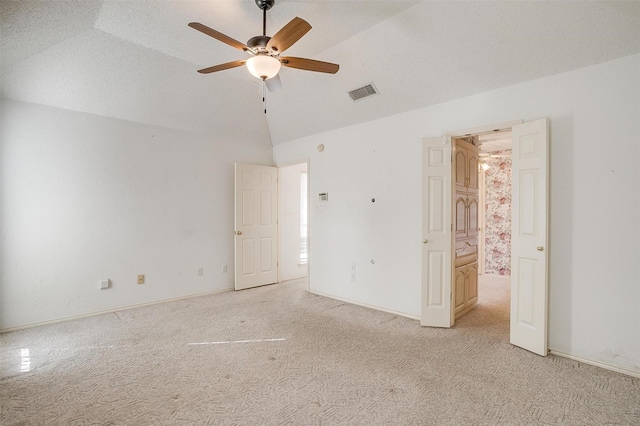 unfurnished bedroom with vaulted ceiling, light colored carpet, ceiling fan, and a textured ceiling