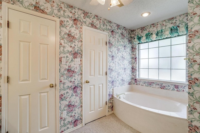 bathroom with a tub to relax in and a textured ceiling