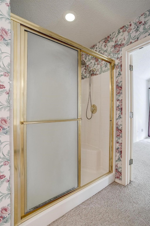 bathroom featuring a shower with shower door and a textured ceiling